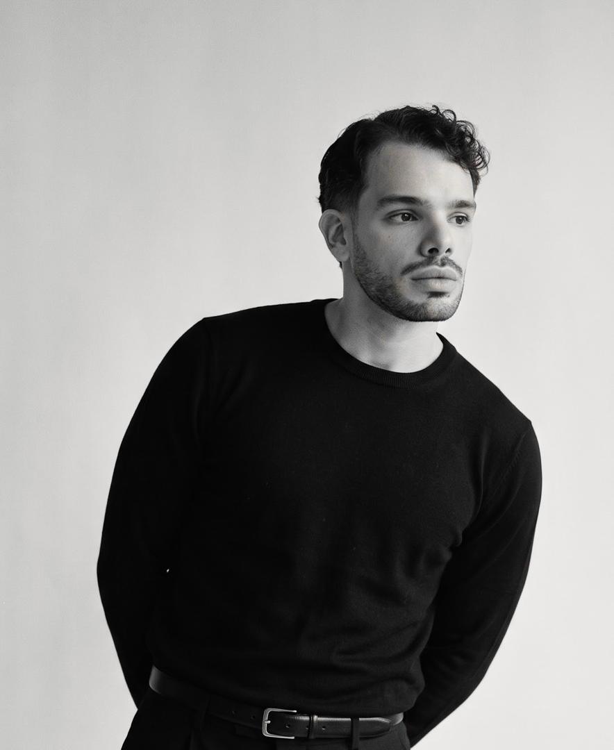 Retrato en blanco y negro de Carlos Colli, con ropa oscura y fondo claro